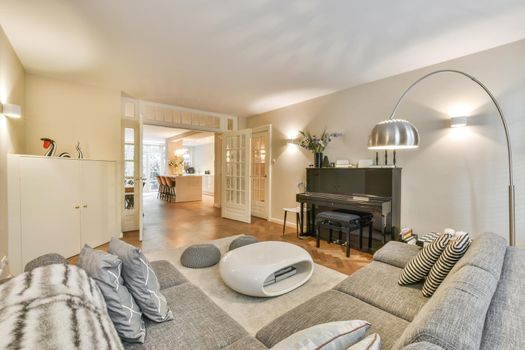 Comfortable sofa and armchair placed on soft carpet near windows in cozy light living room in modern flat