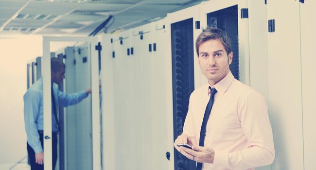 young business man computer science engeneer talking by cellphone at network datacenter server room asking  for help and fast solutions and services