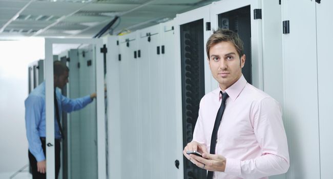 young business man computer science engeneer talking by cellphone at network datacenter server room asking  for help and fast solutions and services