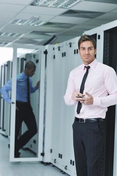 young business man computer science engeneer talking by cellphone at network datacenter server room asking  for help and fast solutions and services