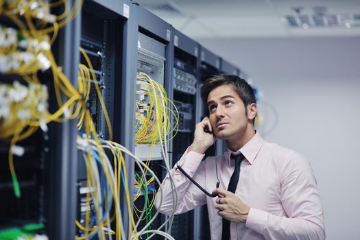 young business man computer science engeneer talking by cellphone at network datacenter server room asking  for help and fast solutions and services