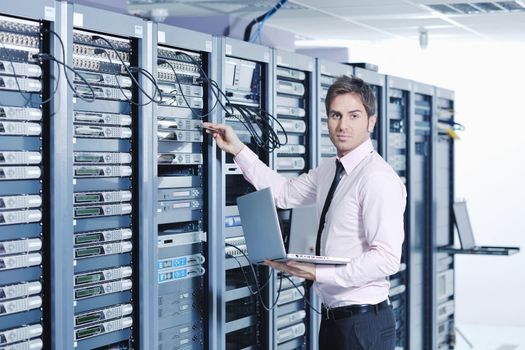 young engeneer business man with thin modern aluminium laptop in network server room