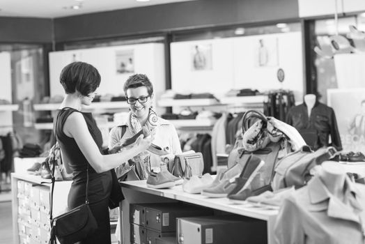 Two Girl-Friends On Shopping Walk On Shopping Centre With Bags And Choosing