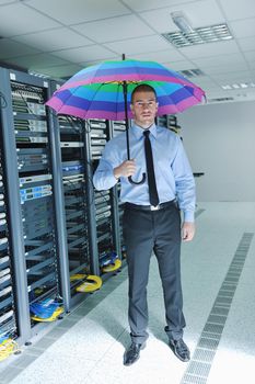 young handsome business man  engineer in 
businessman hold  rainbow colored umbrella in server datacenter room  and representing security and antivirus sofware protection concept