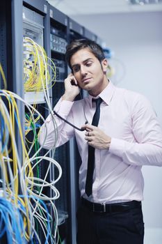 young business man computer science engeneer talking by cellphone at network datacenter server room asking  for help and fast solutions and services