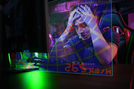 Photo of professional young caucasian gamer playing online on his PC in gaming club or cyber arena. He looks displeased and upset. Game plan went wrong. laser screen, projector, augmented reality, AR, VR