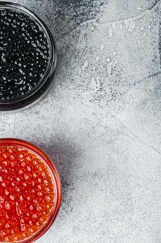 Red and black caviar in glass bowl, on gray background, top view flat lay with copy space for text