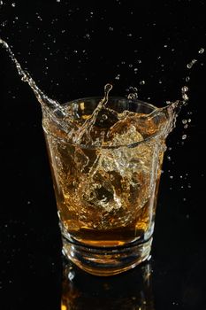 glass of whiskey into which ice falls. frozen splashing drops. High quality photo