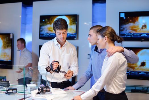 people in consumer electronics  retail store looking at latest laptop, television and photo camera to buy