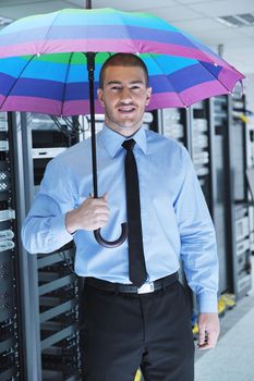 young handsome business man  engineer in 
businessman hold  rainbow colored umbrella in server datacenter room  and representing security and antivirus sofware protection concept