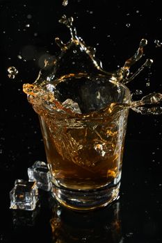 glass of whiskey into which ice falls. frozen splashing drops. High quality photo