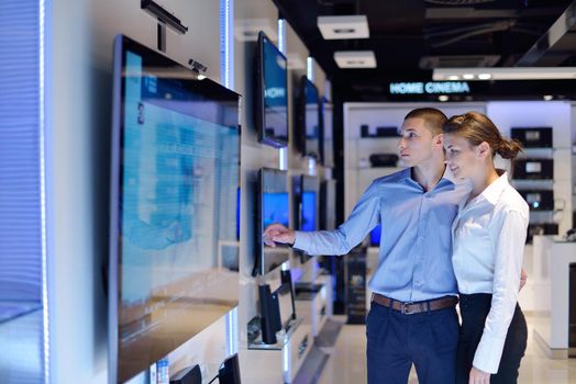 people in consumer electronics  retail store looking at latest laptop, television and photo camera to buy