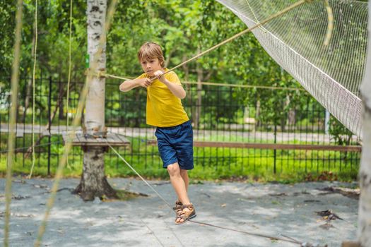 Little boy in a rope park. Active physical recreation of the child in the fresh air in the park. Training for children.