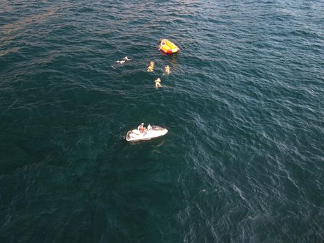 Inflatable attraction. Happy people are going to swim on an air mattress behind a jet ski. Tourists ride the inflatable watercraft boat. Jet ski skating people on a large Inflatable raft