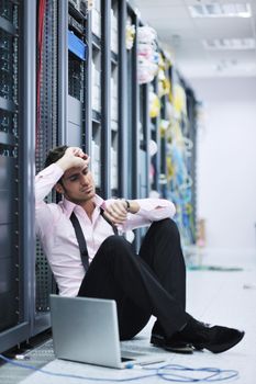 young engeneer business man with thin modern aluminium laptop in network server room