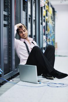 young engeneer business man with thin modern aluminium laptop in network server room