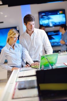 people in consumer electronics  retail store looking at latest laptop, television and photo camera to buy