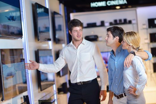 people in consumer electronics  retail store looking at latest laptop, television and photo camera to buy