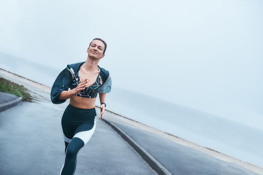My everyday motivation. Happy and strong disabled woman in sportswear is running outdoors near the sea and smiling. Sport concept. Disabled Sportsman
