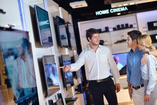 people in consumer electronics  retail store looking at latest laptop, television and photo camera to buy