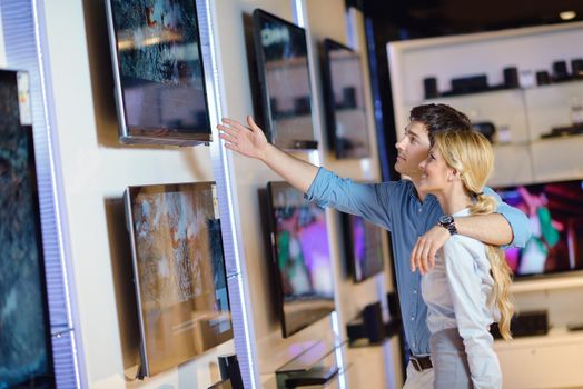 people in consumer electronics  retail store looking at latest laptop, television and photo camera to buy