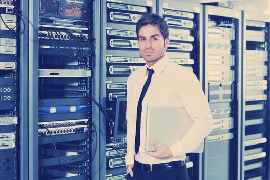 young engeneer business man with thin modern aluminium laptop in network server room