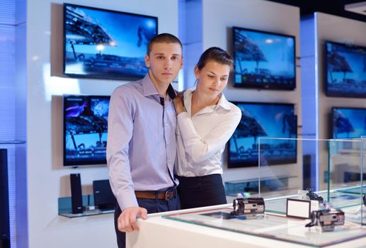 people in consumer electronics  retail store looking at latest laptop, television and photo camera to buy