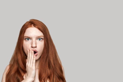 I don't believe Studio shot of cute redhead surprised girl making shocked face while standing against grey background. Human emotions