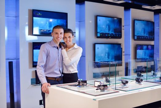 people in consumer electronics  retail store looking at latest laptop, television and photo camera to buy