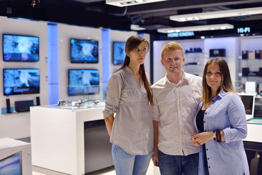 people in consumer electronics  retail store looking at latest laptop, television and photo camera to buy