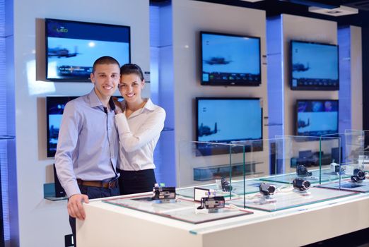 people in consumer electronics  retail store looking at latest laptop, television and photo camera to buy