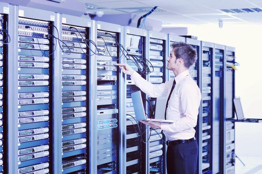 young engeneer business man with thin modern aluminium laptop in network server room