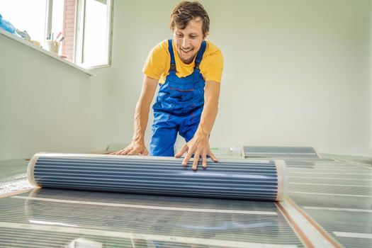 Master installs film warm floor in the room. Floor heating installation.