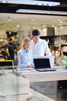 people in consumer electronics  retail store looking at latest laptop, television and photo camera to buy