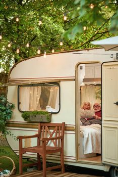 Elderly gray-haired man and woman holding a map while lying on couch in their camper van. Travel concept