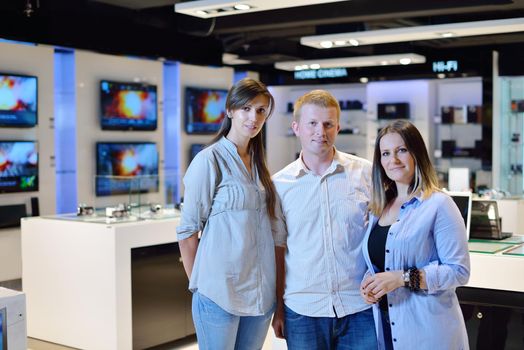 people in consumer electronics  retail store looking at latest laptop, television and photo camera to buy