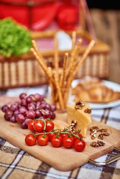 Close up of picnic setting with delicious food with a wicker basket in the background. Rest and vacation lifestyle concept