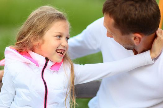 Happy father and his adorable little daughter outdoors looking at each other