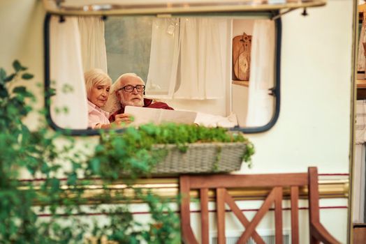Senior couple carefully looking at the new route on the map while relaxing in their camper van. Travel concept