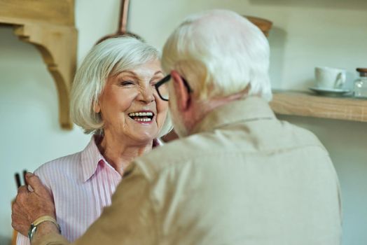 Smiling beautiful elderly woman looking at her husband at their kitchen. Family and relationships concept