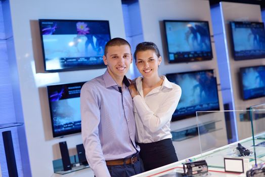 people in consumer electronics  retail store looking at latest laptop, television and photo camera to buy