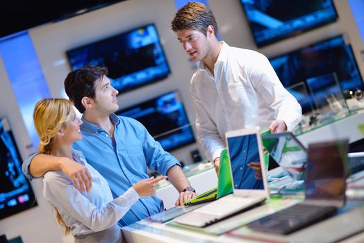 people in consumer electronics  retail store looking at latest laptop, television and photo camera to buy