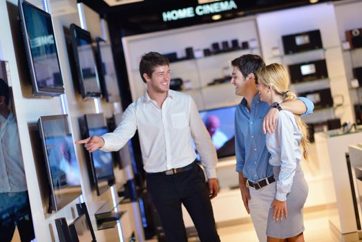 people in consumer electronics  retail store looking at latest laptop, television and photo camera to buy