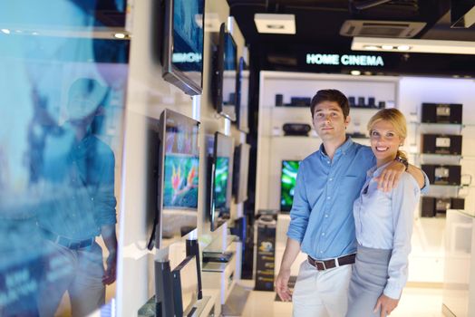 people in consumer electronics  retail store looking at latest laptop, television and photo camera to buy