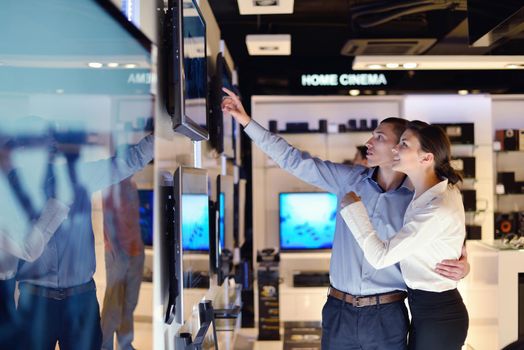 people in consumer electronics  retail store looking at latest laptop, television and photo camera to buy