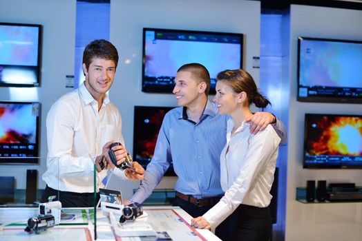 Young couple in consumer electronics store looking at latest laptop, television and photo camera to buy