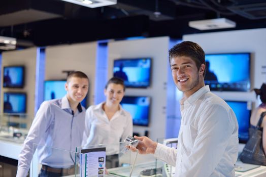 people in consumer electronics  retail store looking at latest laptop, television and photo camera to buy