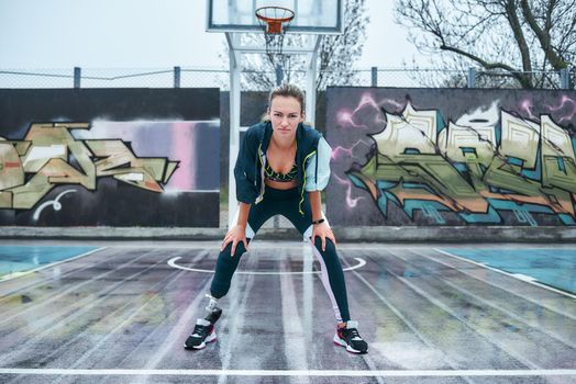 Be stronger. Young healthy disabled woman is standing on stadium and looking at camera while doing her morning workout. Sport concept. Disabled Sportsman