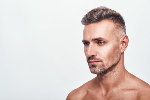 I need to shave. Side view of handsome and sexy man with a stubble looking aside while standing against grey background. Men beauty. Skin care