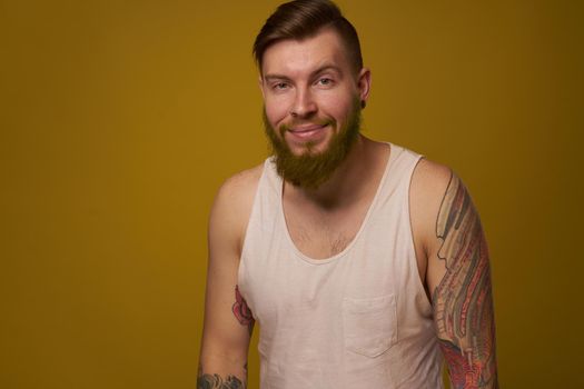 Cheerful bearded man in a white T-shirt with hooligan tattoos on his arms. High quality photo